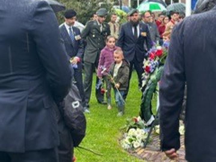 Kinderen met roos in hun hand bij het monument